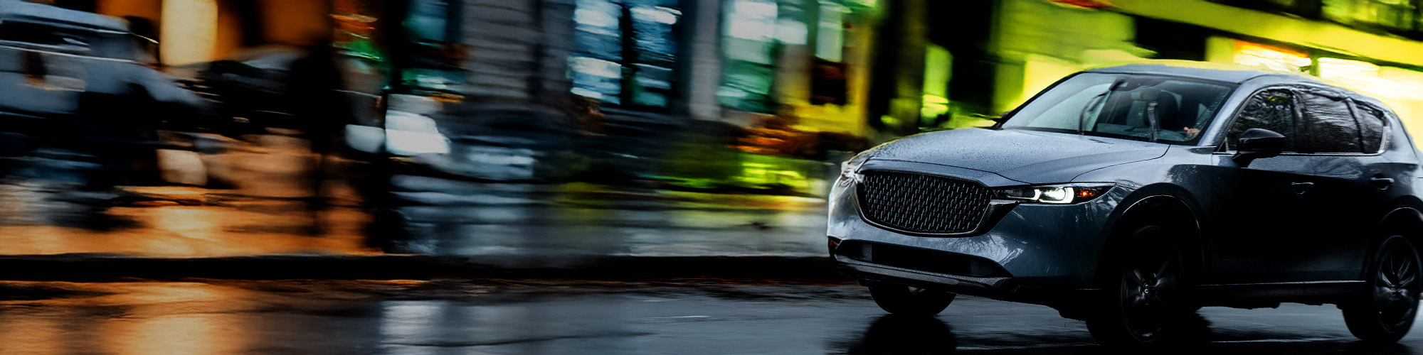 VUS circulant sur des rues urbaines mouillées la nuit démontrant l’adhérence et le contrôle des pneus Blackhawk